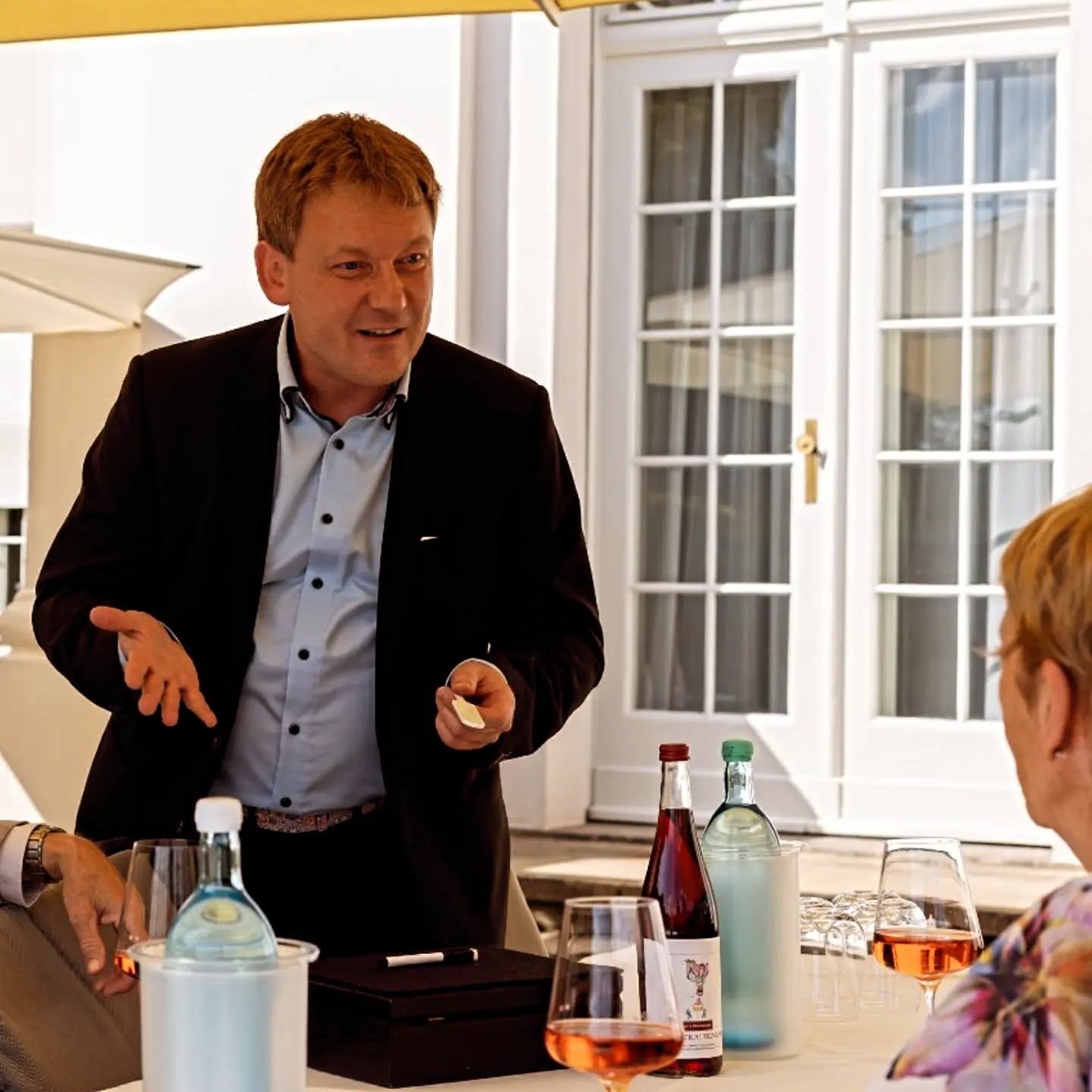 Mann im Anzug zaubert für Gäste am Tisch.